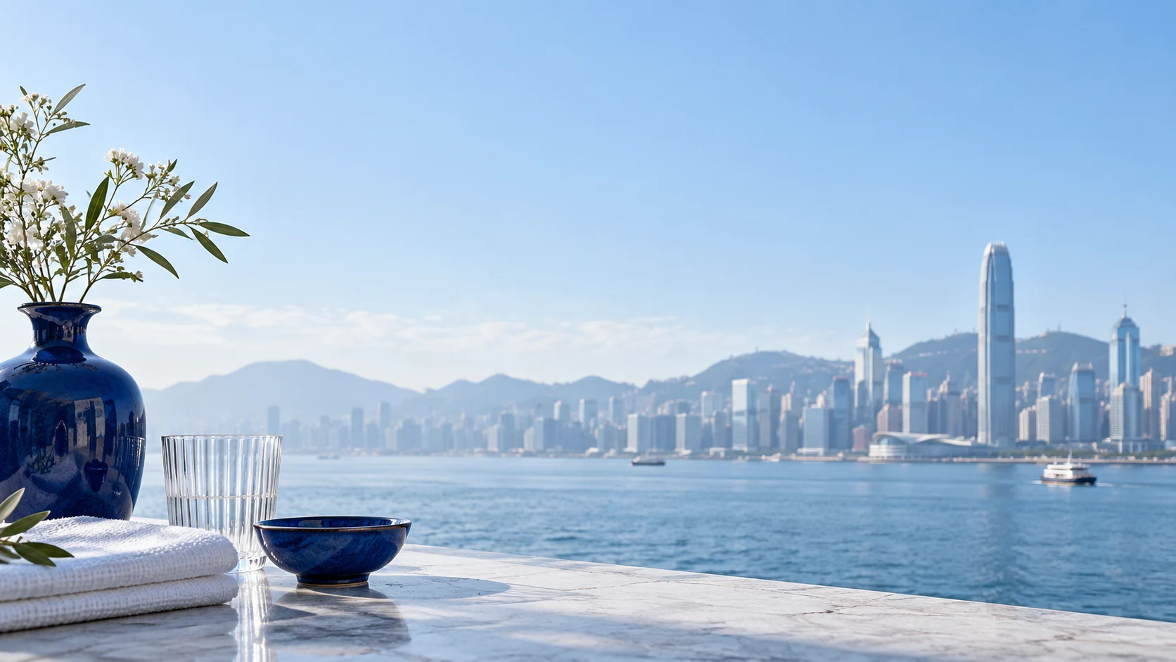 日光下的香港海港背景,前景為鈷藍陶瓷花瓶與碗、白色亞麻布和直紋透明玻璃器皿